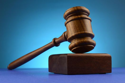 A legal gavel and block over a blue background.