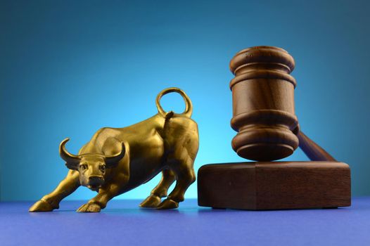 A bull and legal gavel block over a blue background.