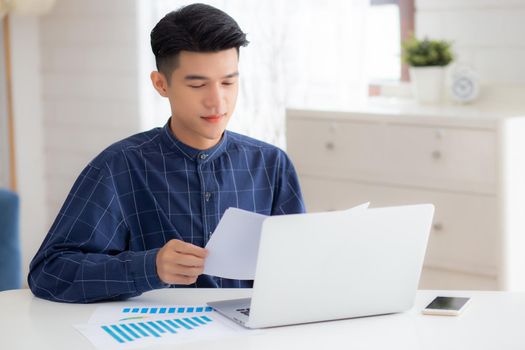 Young asian business man looking document data graph and chart paper, marketing and investment, report of statistics profit for financial, economic and growth of finance, management and planning.