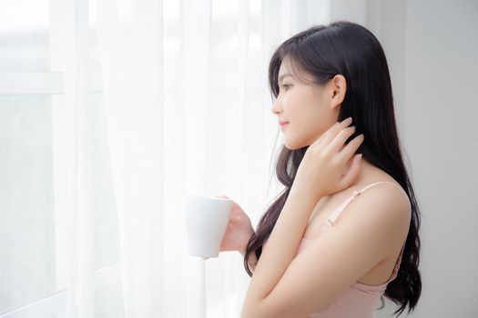 Beautiful young asian sexy woman in underwear drinking coffee near windows in the morning, girl with seductive figure fit drinking beverage for relax and resting after wake up, lifestyle concept.