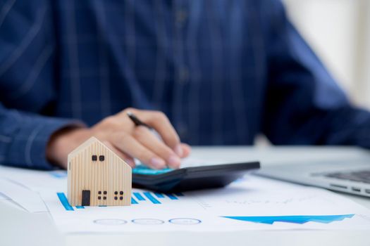 Hand of business man agent calculating loan of finance and investment for real estate, businessman and invest in property about home, construction or mortgage of home, male using calculator.