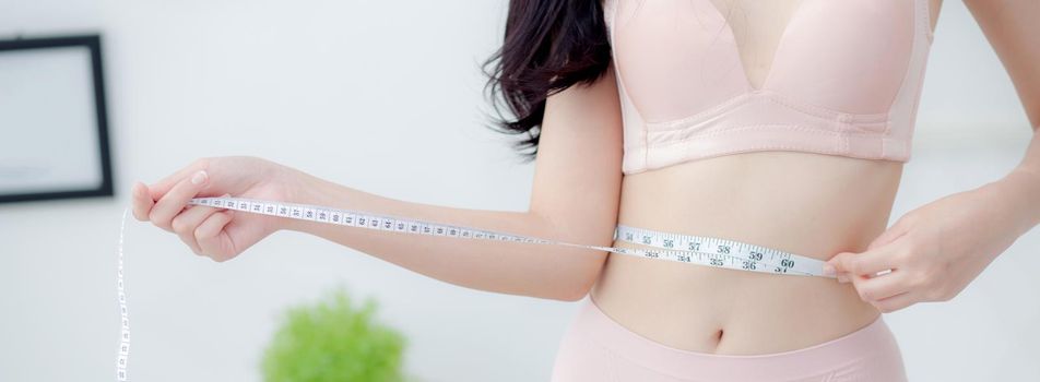 Beautiful young asian woman sexy body slim measuring abdomen for control weight loss in the room, beauty girl belly thin have cellulite with tape measure for diet, health concept, banner website.