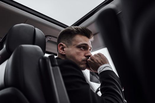 Confident young businessman sitting at the wheel of his new car. Rent and trade-in concept