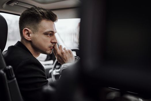 Cropped photo of confident businessman sitting at the wheel of automobile. Rent and trade-in concept