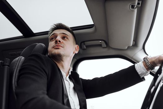 Cropped photo of young handsome man looking away while driving car. Rent and trade-in concept