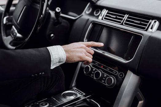 Cropped photo of businessman changing stations on his automobile radio. Transportation and vehicle concept