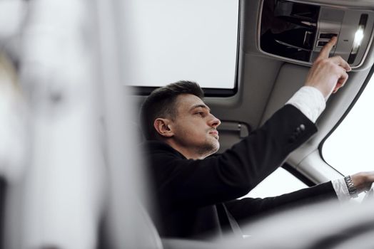 Cropped photo of handsome man renting modern automobile while pushing button. Rent and trade-in concept