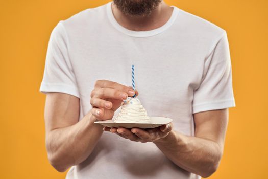 A man with a birthday cake in his hands on a yellow background birthday dessert. High quality photo