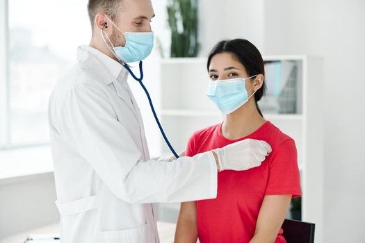 patient being examined by a doctor wearing a medical mask, protective gloves and a stethoscope. High quality photo