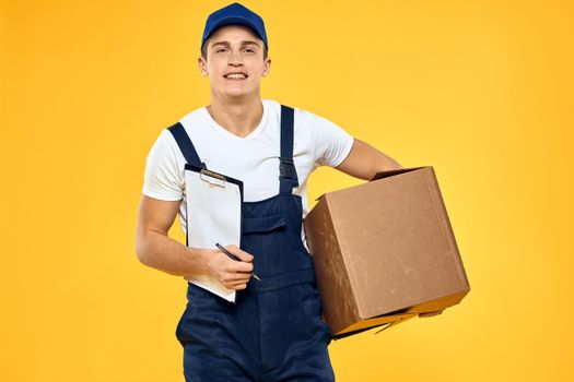 A man with a box in his hands working uniform that delivery service yellow background. High quality photo