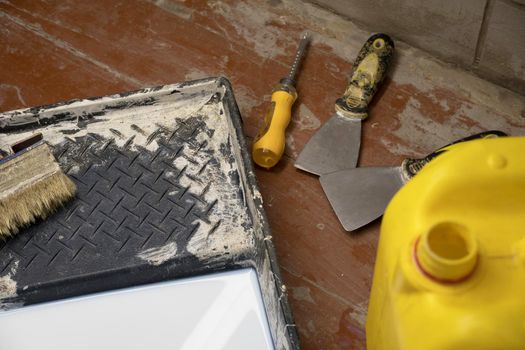 Construction and painting tools lie on the floor during the repair and restoration of the house.Work as a Builder or handyman in the house.Finishing or repairing a room.Job of repairing the apartment