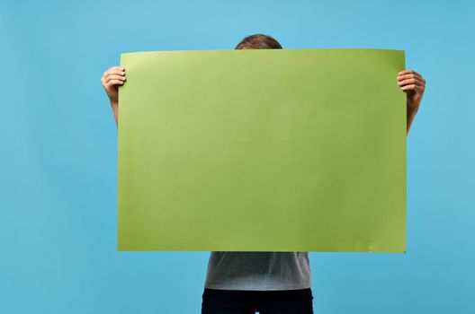 man holding green banner marketing copy space blue advertising background. High quality photo