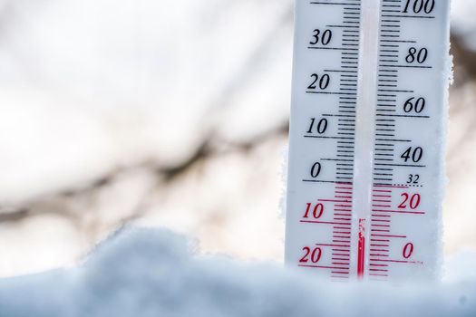 The thermometer lies on the snow in winter showing a negative temperature. Meteorological conditions in a harsh climate in winter with low air and ambient temperatures.Freeze in wintertime