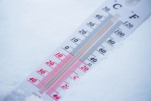 The thermometer lies on the snow in winter showing a negative temperature. Meteorological conditions in a harsh climate in winter with low air and ambient temperatures.Freeze in wintertime