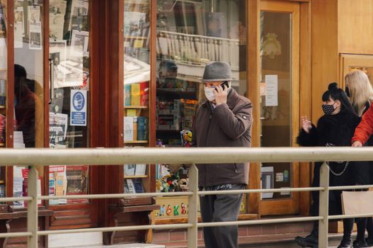 Unidentified person with face protection talks with his mobile phone at an urban environment.