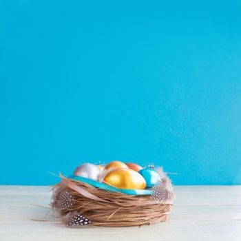 Beautiful Happy Easter holiday greeting banner with easter nest with colored eggs and decorated with ribbons over light wooden background with copy space for text on blue