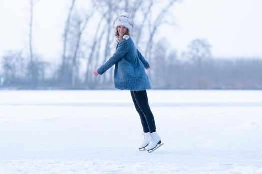 Gorgeous woman skating on frozen lake.