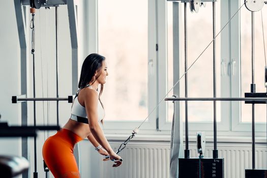 woman training on a pulley machine in the gym.