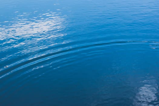 Small ripples on calm water with deep blue reflections.