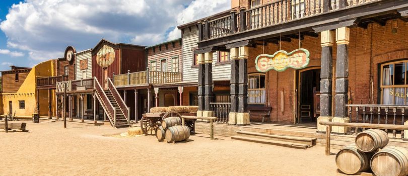 Vintage Far West town with saloon. Old wooden architecture in Wild West with blue sky background.