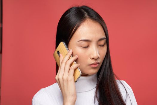 woman asian appearance talking on the phone lifestyle technology red background. High quality photo