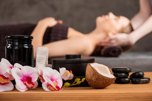 Beautiful woman getting head massage in spa orchid flowers coconut and stones