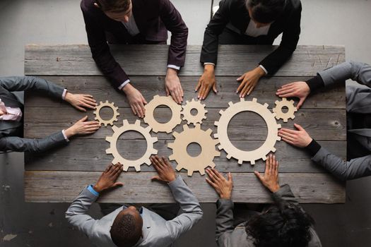 Business people connect golden gear together at meeting table, success cooperation teamwork concept