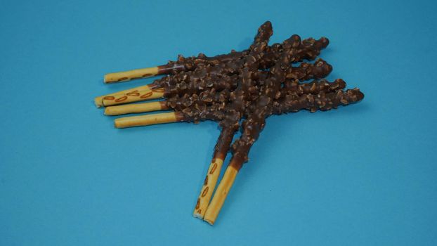 Chocolate crispy sticks with hazelnut sprinkles on a blue background.