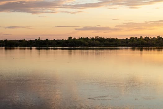 Colorful sunny sunset on a calm lake. The sun is reflected on the surface of the water.