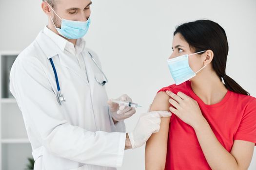 the doctor makes an injection into the patient's arm with a medical mask plan. High quality photo