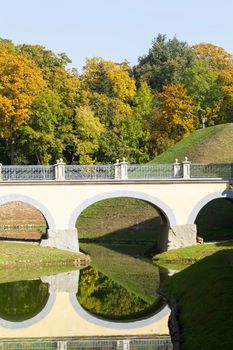 Beautiful vertical landscape with an autumn forest, a river and an ancient bridge.