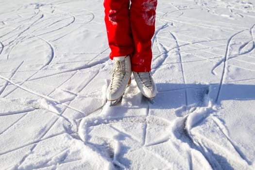 Legs of skater on winter ice rink in outdoors