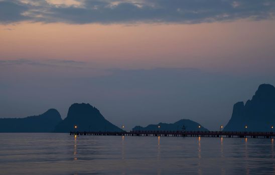 The scenery of the bridge stretching into the sea behind the mountain range in the morning.