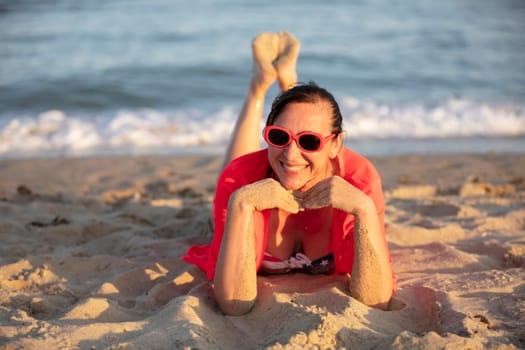 Happy middle-aged woman on the coast looks at the camera and smiles.