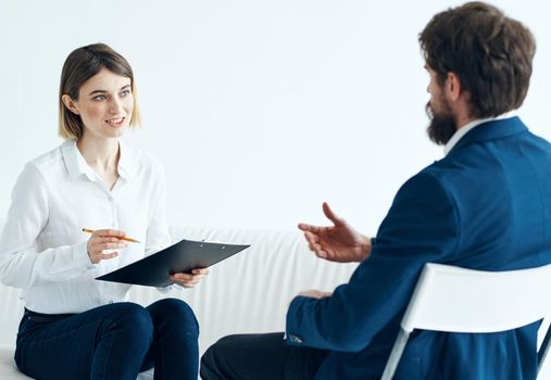 A woman with documents listens to the problems of a man on a light background psychologist. High quality photo