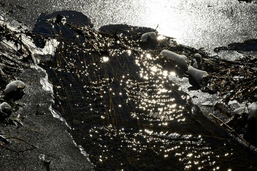 little creek in wiinter with ice in back light