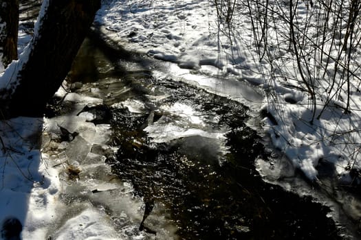 little creek in wiinter with ice in back light