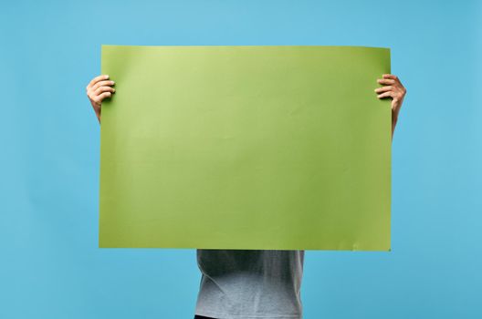 man holding green banner marketing copy space blue advertising background. High quality photo