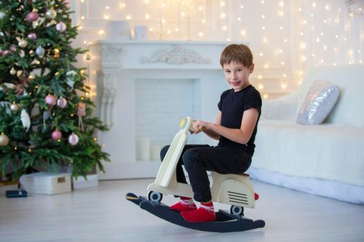 Handsome little boy in casual clothes is playing in the Christmas room.
