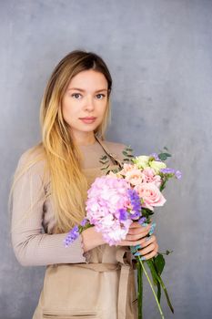 Young caucasian female florist collects a romantic bouquet of roses. People in the process of work. The concept of a flower shop and flower delivery as a family business.