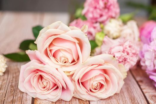 Close-up of different pastel roses in a bouquet on the table at the florist, macro shooting with natural light.
