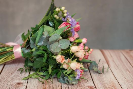 Close up view of a beautiful bouquet of mixed coloful flowers on wooden table. The concept of a flower shop and flower delivery as a family business, florist work.