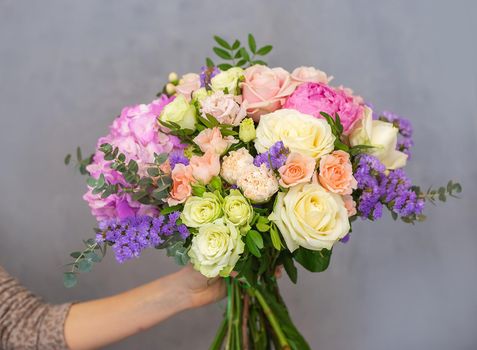 Close up view of a beautiful bouquet of mixed coloful flowers in a florist hand. The concept of a flower shop and flower delivery as a family business, florist work.