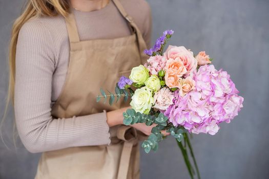 Florist at work. Female hands collect a romantic bouquet of roses. People in the process of work. The concept of a flower shop and flower delivery as a family business.