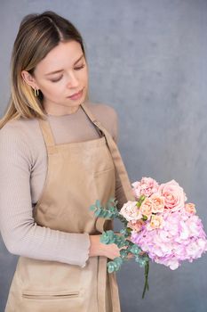 Young caucasian female florist collects a romantic bouquet of roses. People in the process of work. The concept of a flower shop and flower delivery as a family business.