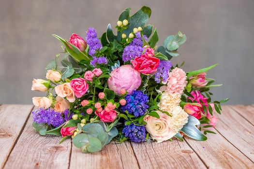 Close up view of a beautiful bouquet of mixed coloful flowers on wooden table. The concept of a flower shop and flower delivery as a family business, florist work.