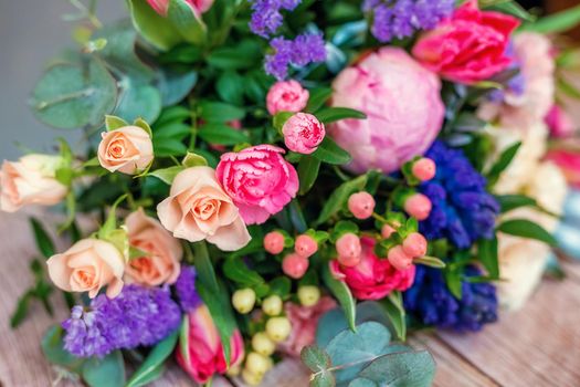 Close up view of a beautiful bouquet of mixed coloful flowers on wooden table. The concept of a flower shop and flower delivery as a family business, florist work.