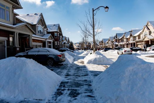 Along the street, next to the sidewalk cleared of snow, there are neat slides of snow