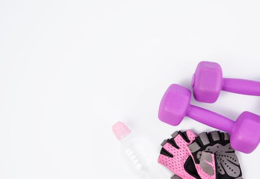 pink sports gloves, pair of purple dumbbells and and bottle of water on a white background, healthy lifestyle