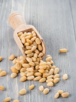 Pine nuts in wooden scoop on gray wooden background